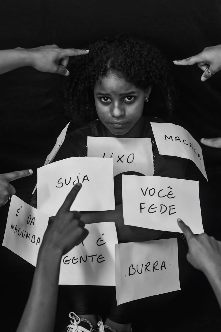 Jovem está cercada por palavras racistas encenadas para denúncia pedagógica