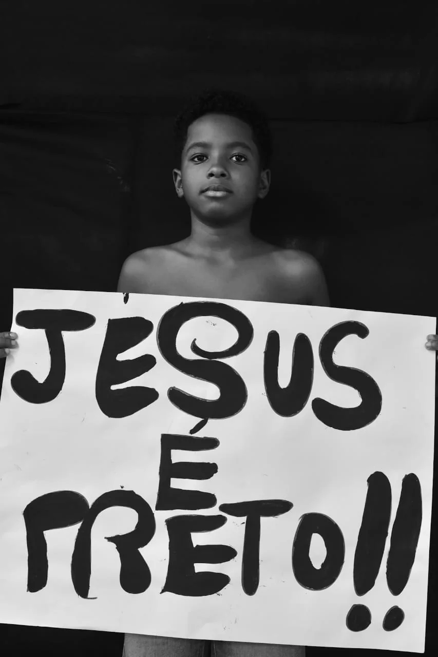 Criança segura um cartaz com a frase Jesus é preto